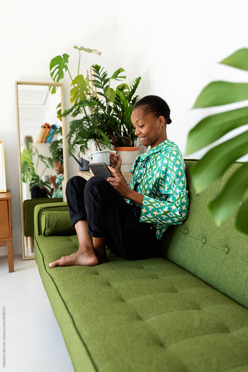Stylish woman with a coffee using her tablet on couch