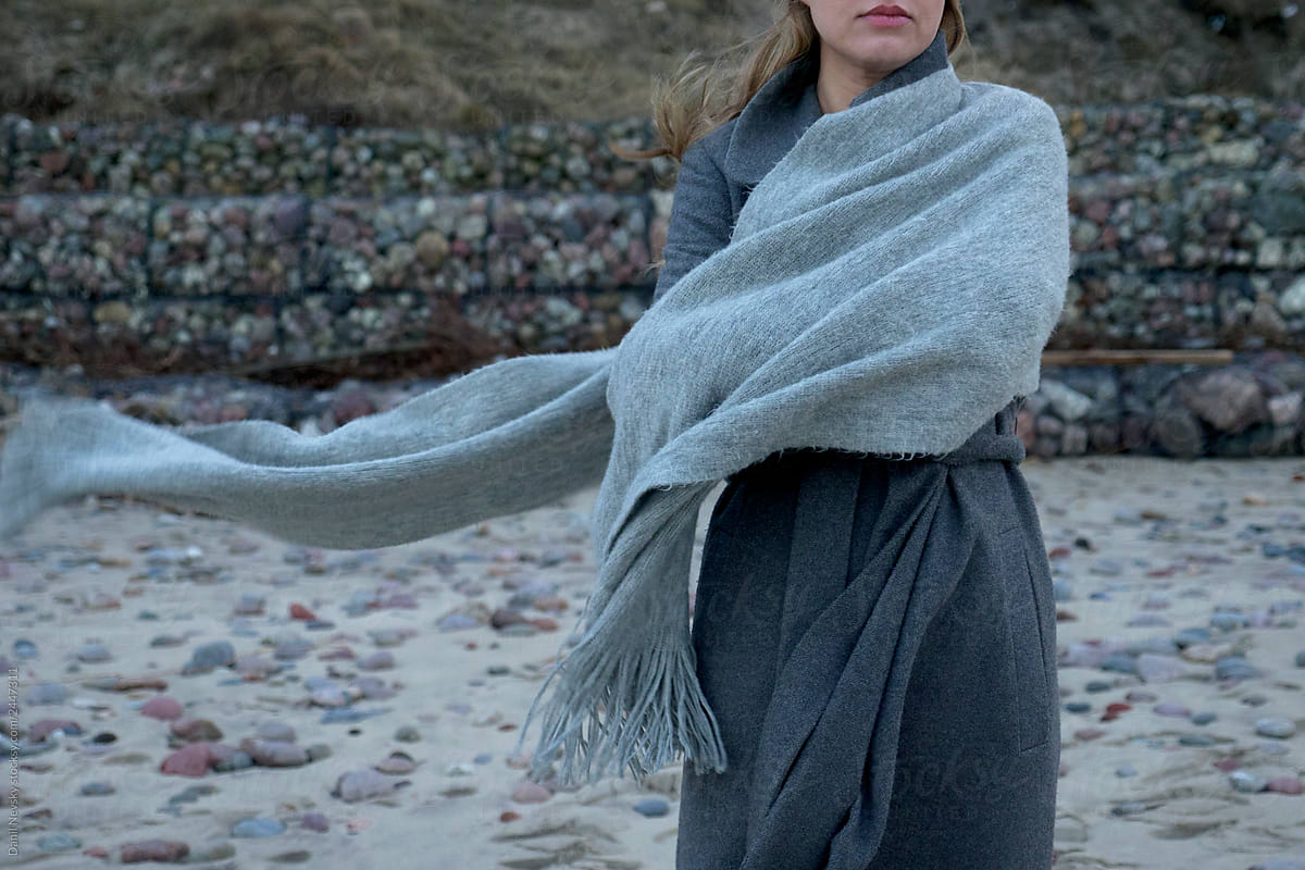 Woman in coat and scarf on beach