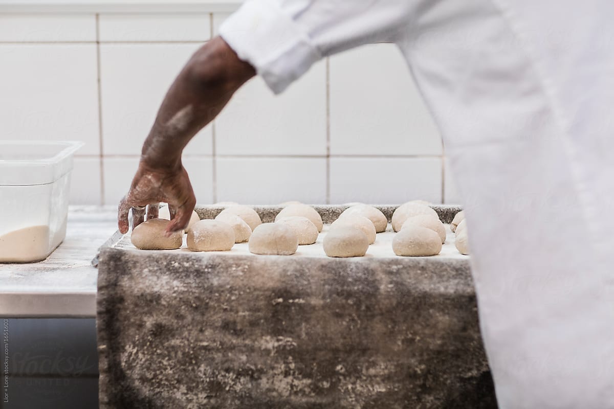 Baker arranging rolls dough on a baking tray