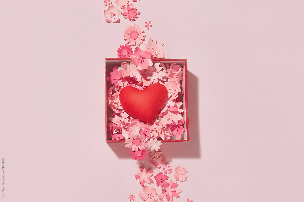 Red heart inside open gift box on pink background with paper art