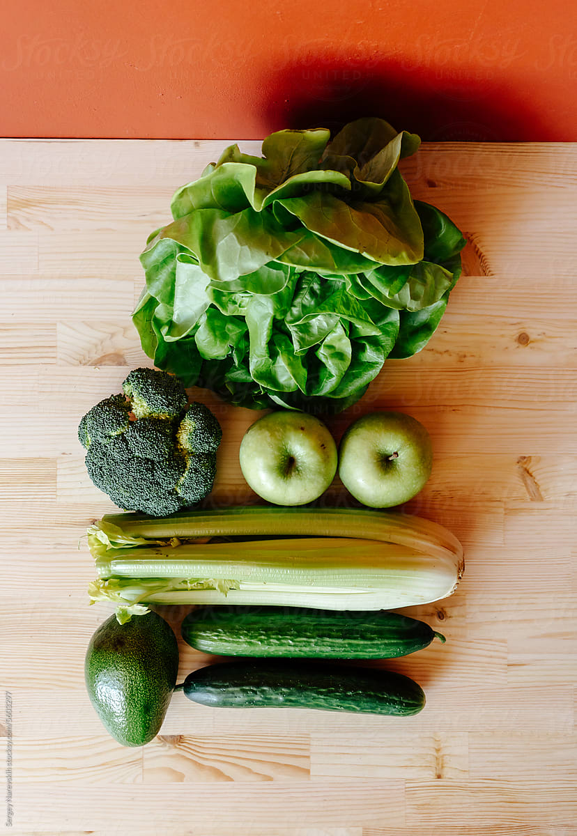 Various green fruits and vegetables on kitchen table