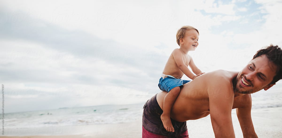Young dad having fun with toddler son on tropical beach