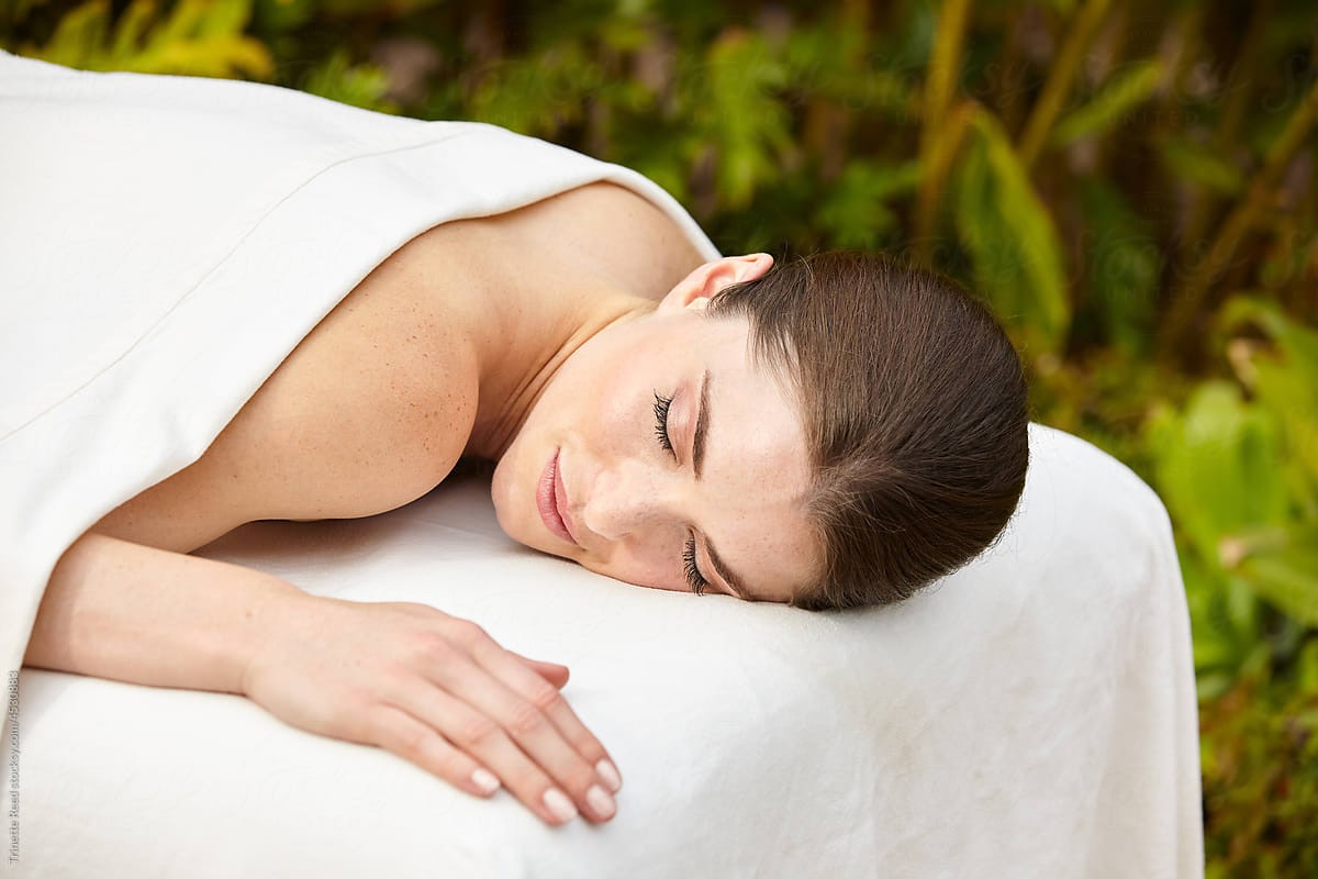 Close-up of beautiful serene woman relaxing on massage table at spa