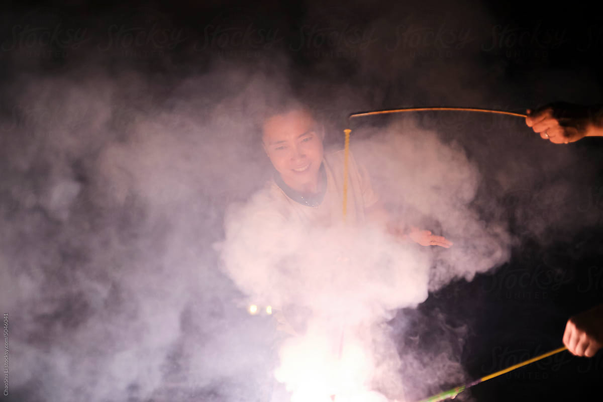 Asian woman, playing fireworks outdoors at night in nature
