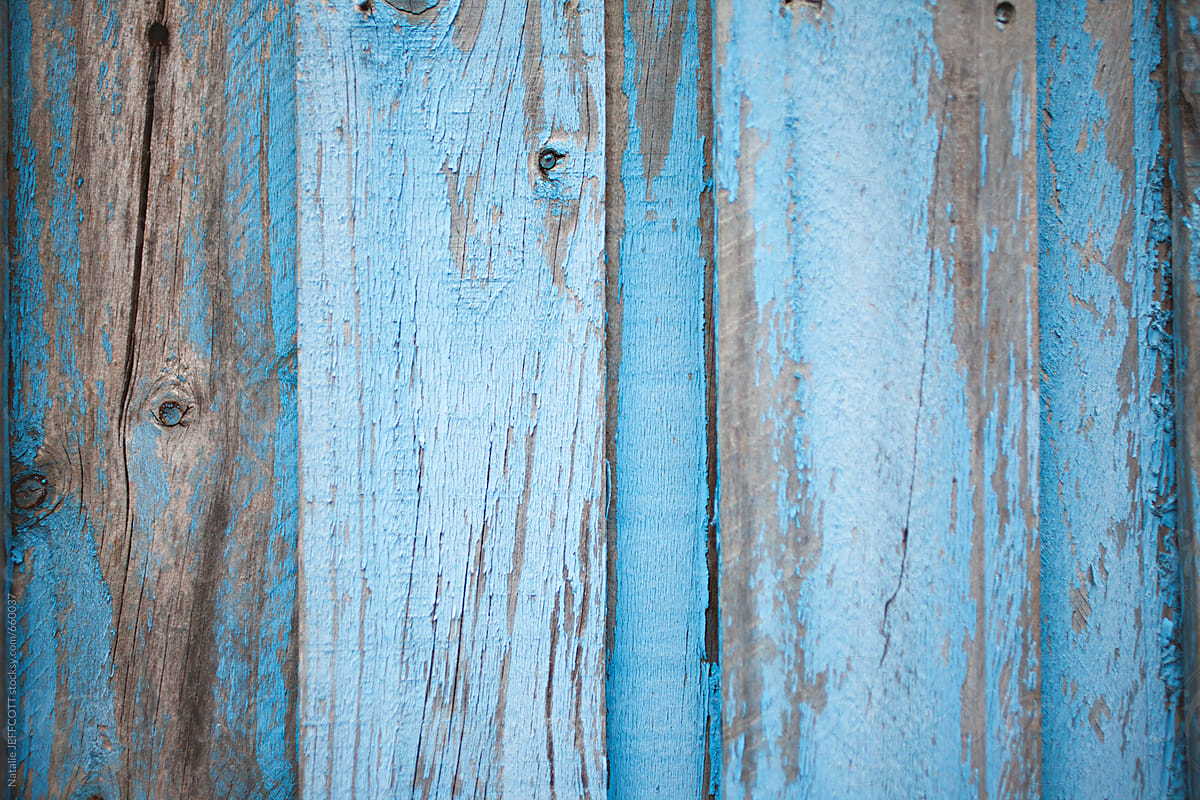 weathered and textured peeling blue paint on a wooden fence