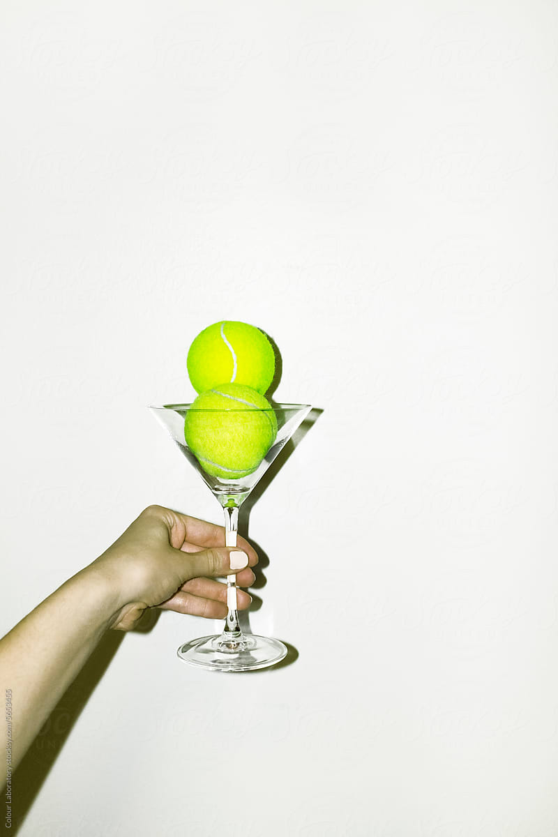 Neon green tennis balls in martini cocktail glass and hard flashlight