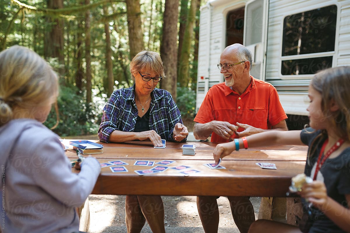 Grandparents enjoying playing cards with kids on campsite