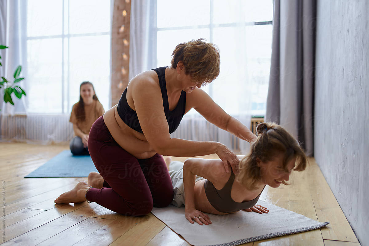 adult mother yoga coach with her daughters doing yoga at home