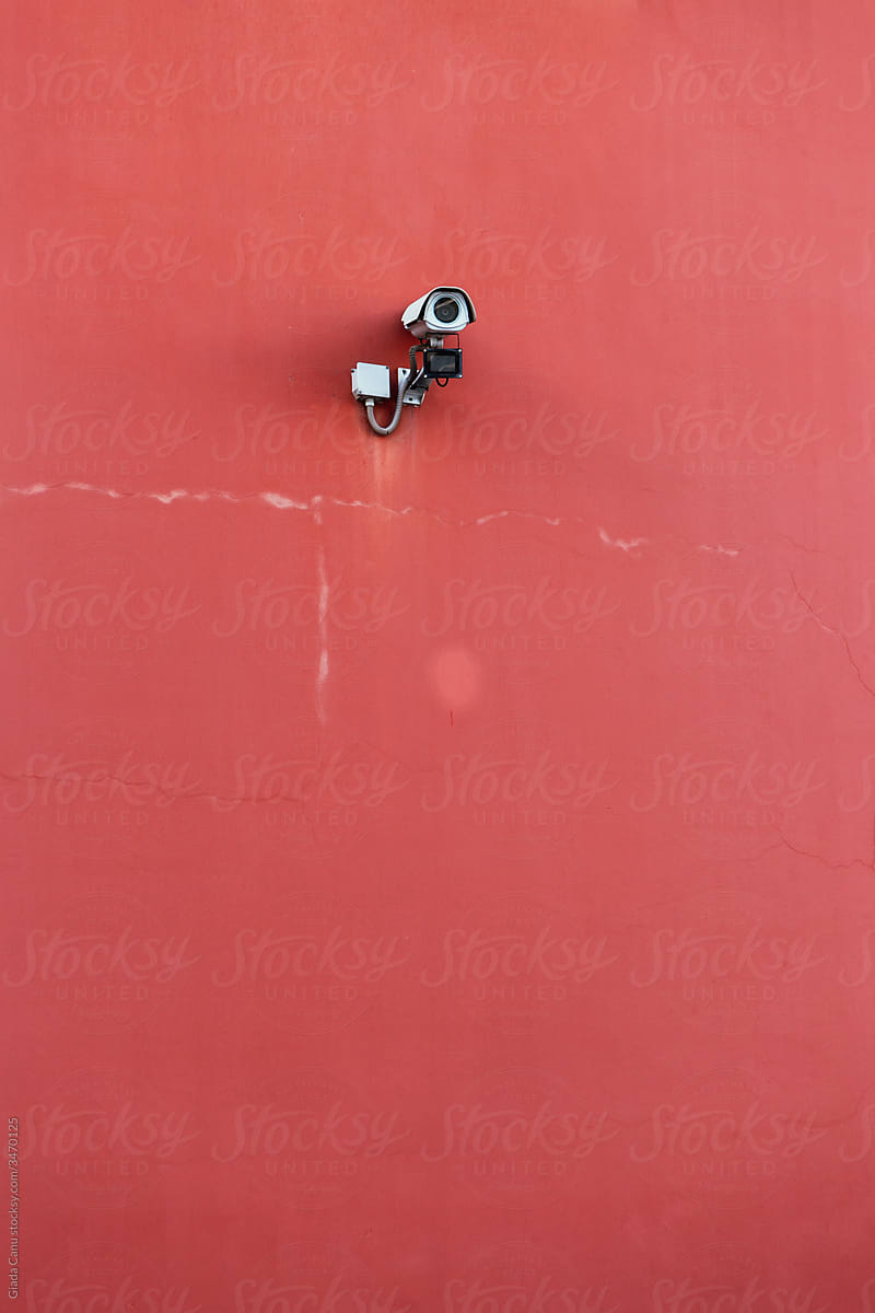 Security camera against a red wall