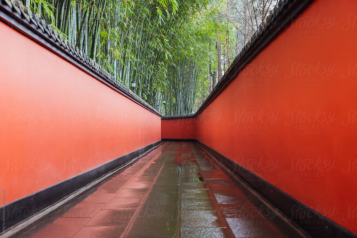 Passage between red walls surrounded by bamboos