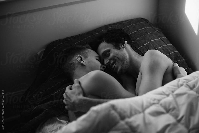 Young gay couple hugging and laughing in bed