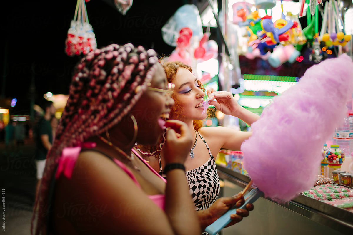 Young girls shopping and having cotton candy at a fair
