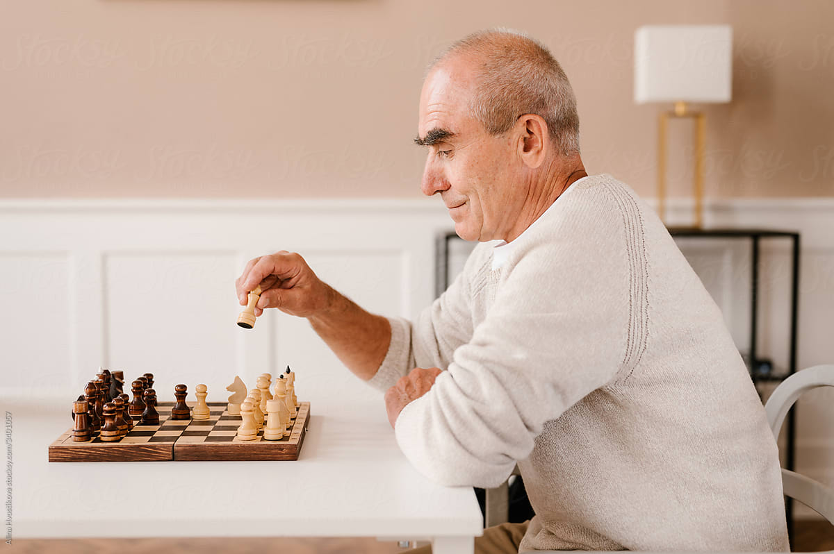 Senior man playing chess game alone