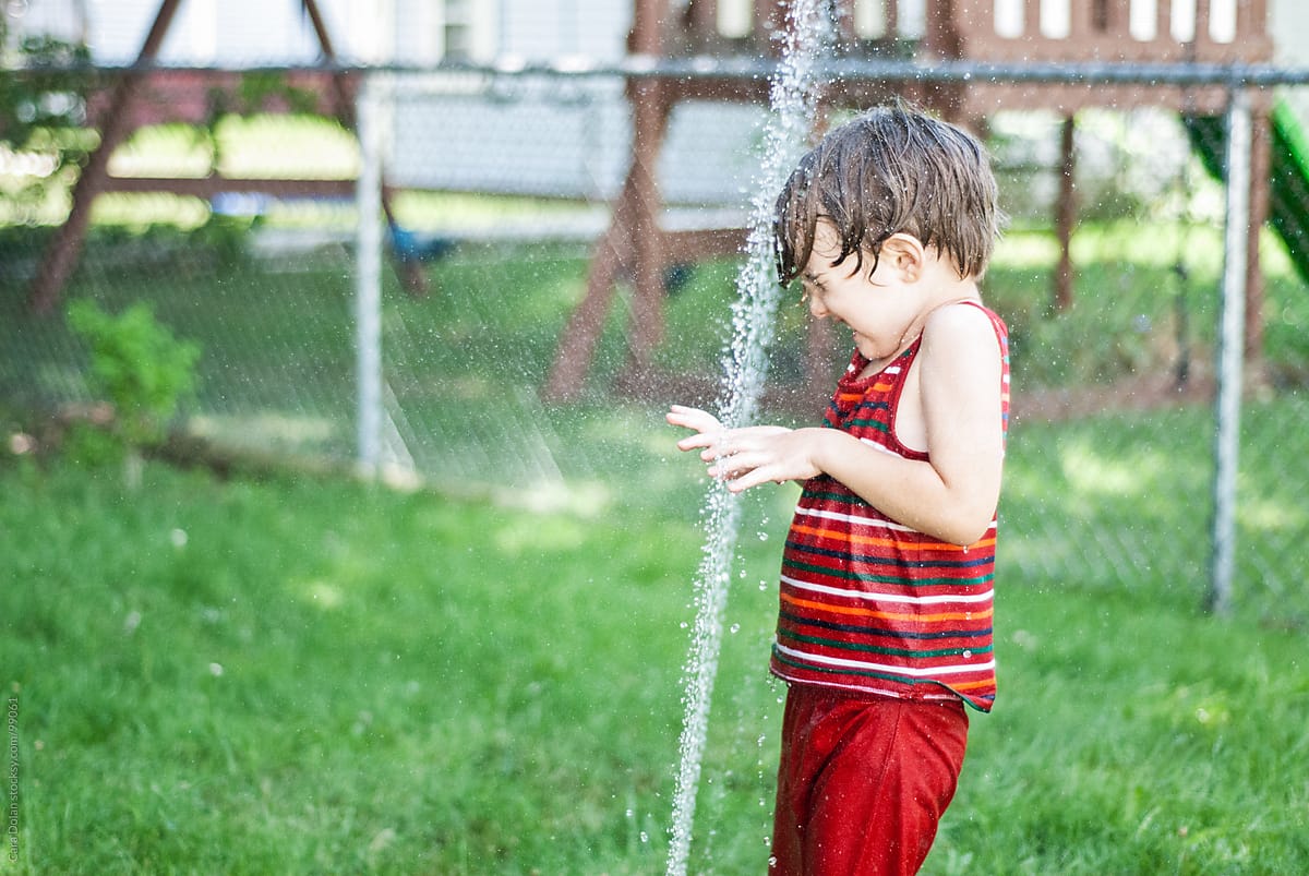 Boy Plays with Backyard Sprinkler in Summer