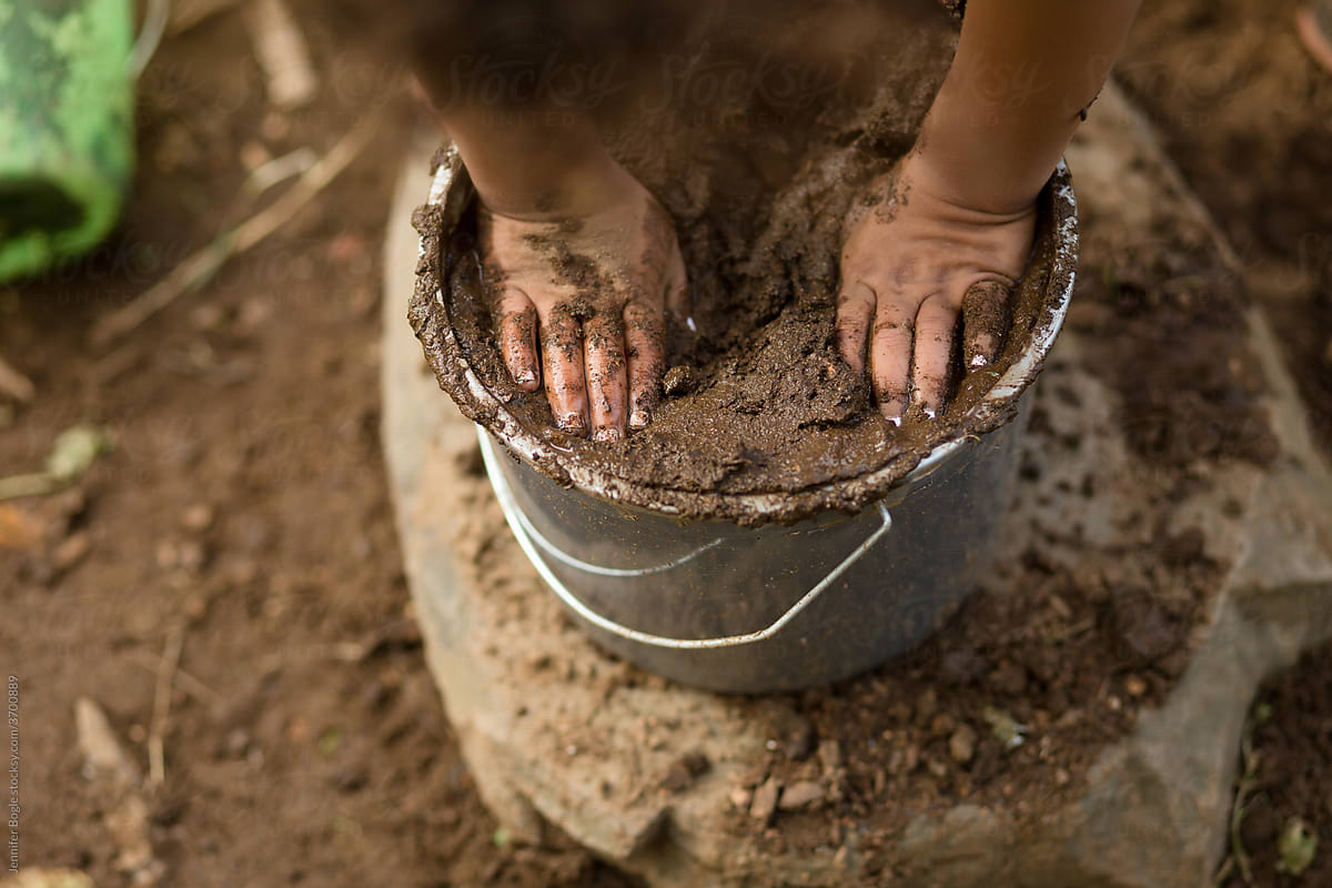 Small child\'s hands in bucket of mud