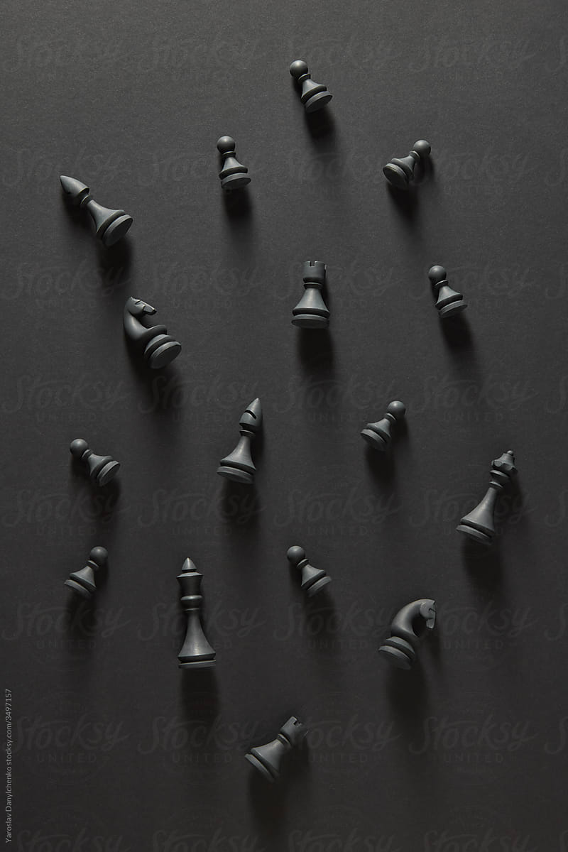 Pattern from black chess figures lying on dark surface.