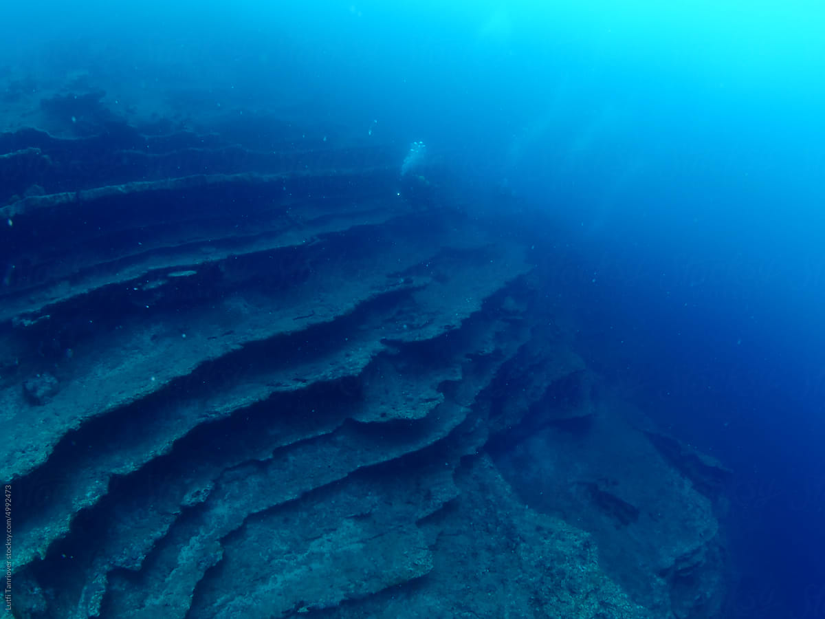 scuba divers exploring strange shape rocks and underwater topography