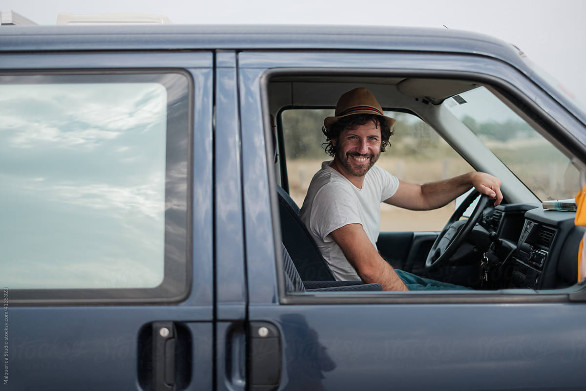 Smiling man drives a camper van