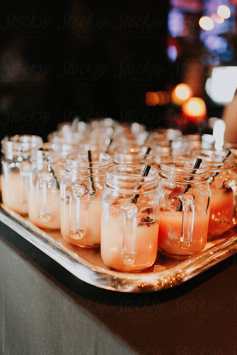 Mason jars filled with orange christmas drinks and black straws