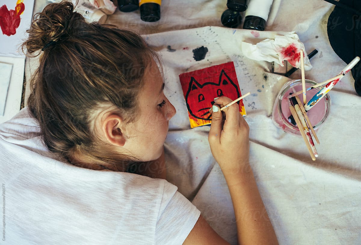Girl painting a cat on a small, square canvas