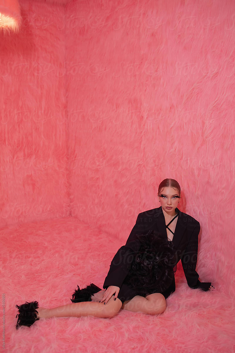 trendy woman in black in pink fur room