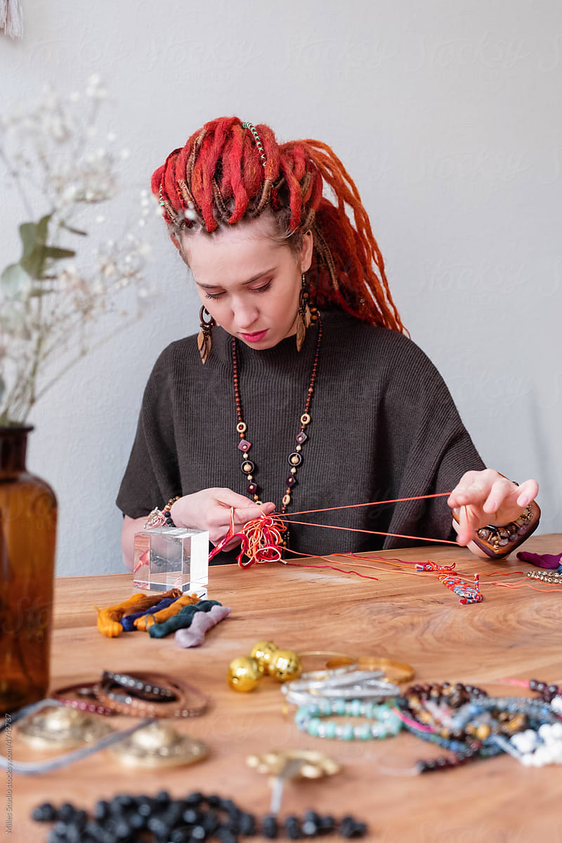 Focused craftswoman tying knots on handmade bracelet