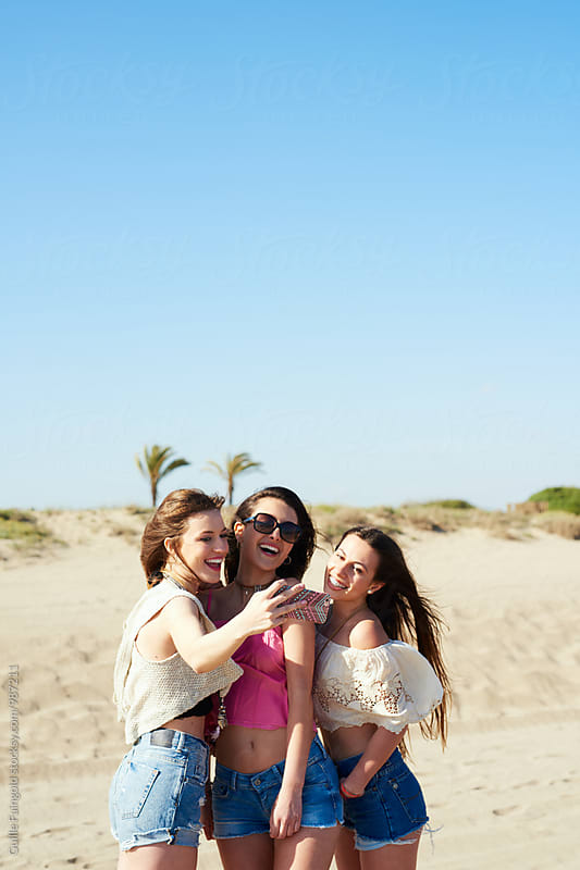 Three girlfriends taking selfie on beach