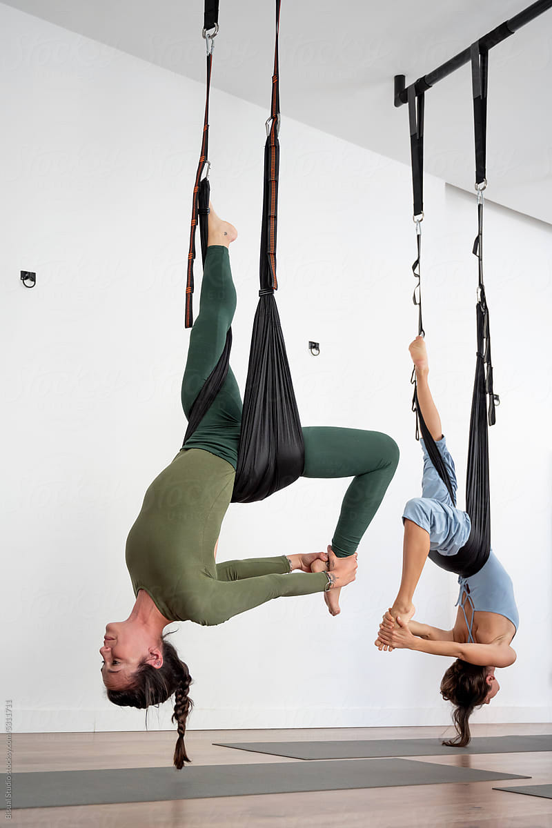 Flexible women doing aerial yoga exercise on ropes