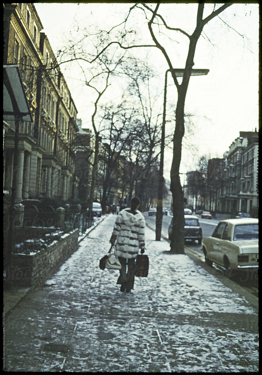 70\'s film photo. Back of woman walking in snowy street in London