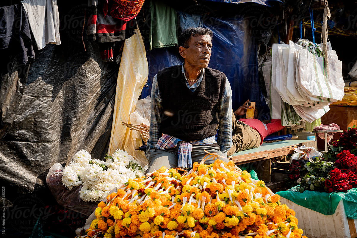 A fresh flower vendor poses for a portrait on the street in Kolkata