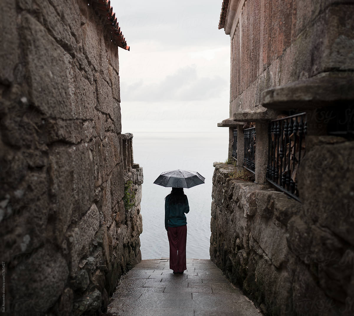 Woman with umbrella at surreal coast village street