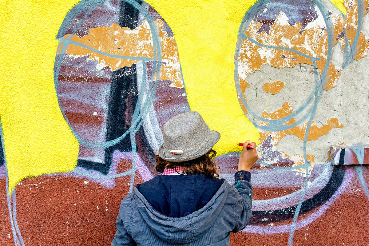 Female graffiti artist painting on wall