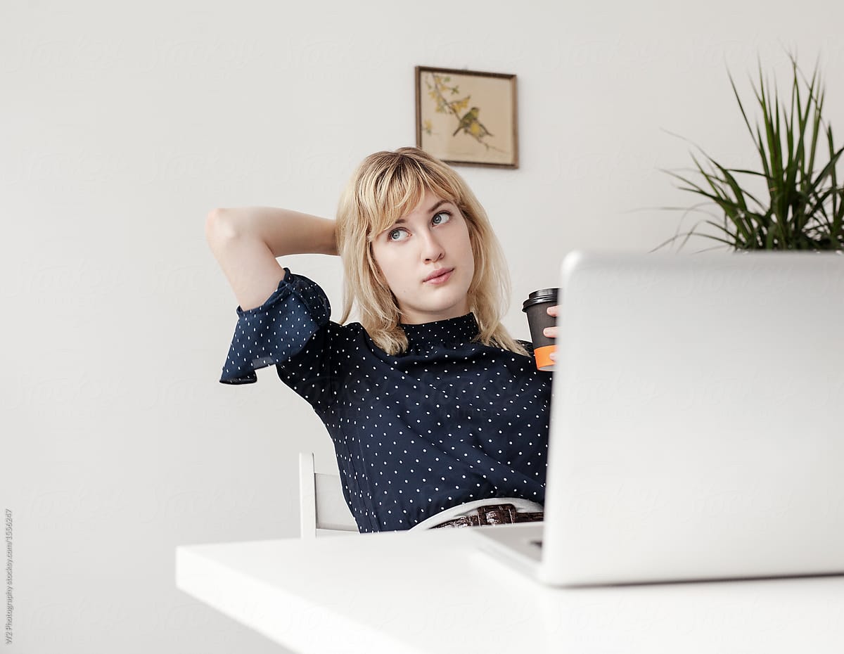 Blonde woman leaning back on her chair taking a break at her desk.