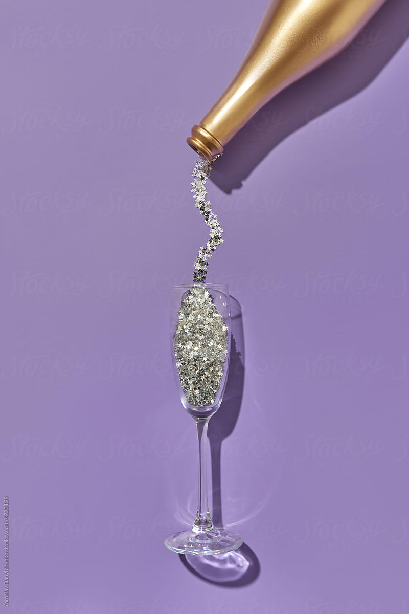 Silver glitter pouring into glass from bottle