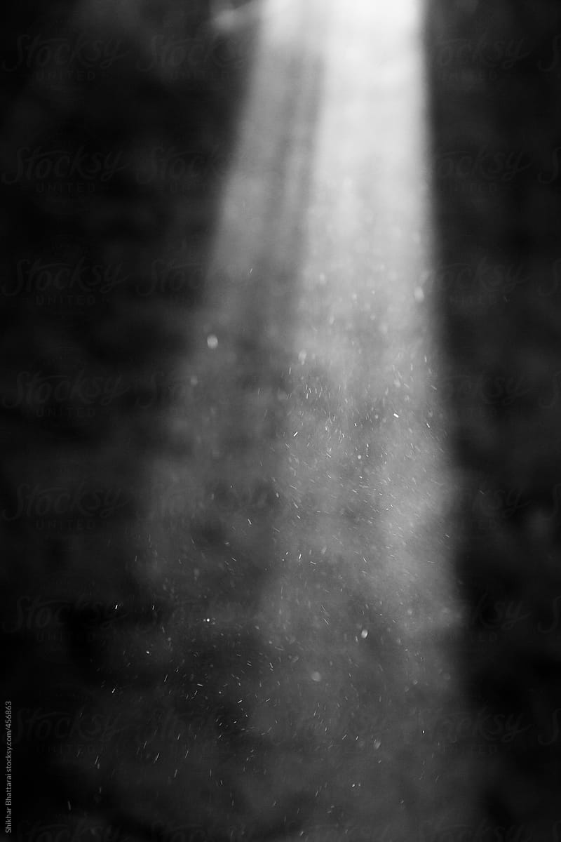 Light rays with small particles floating on smoke filled room seeping through holes.