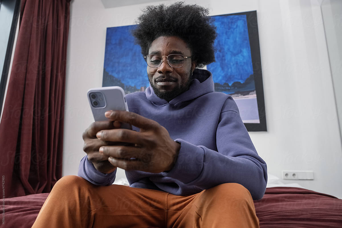 Black man using smartphone in modern bedroom