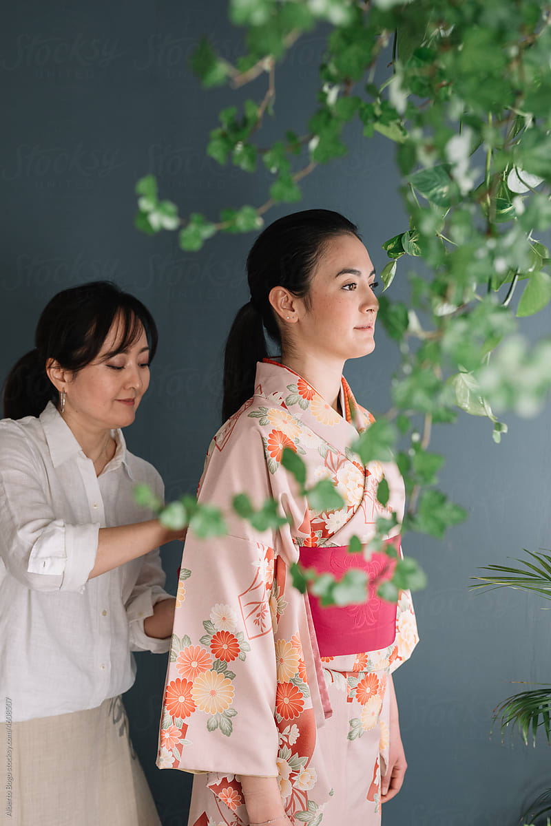 Mother Dressing Daughter With Traditional Kimono