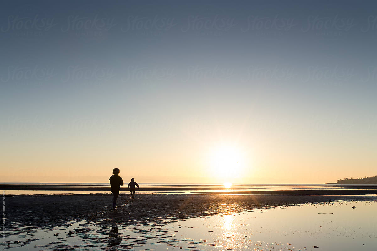 Brothers run on beach at sunset