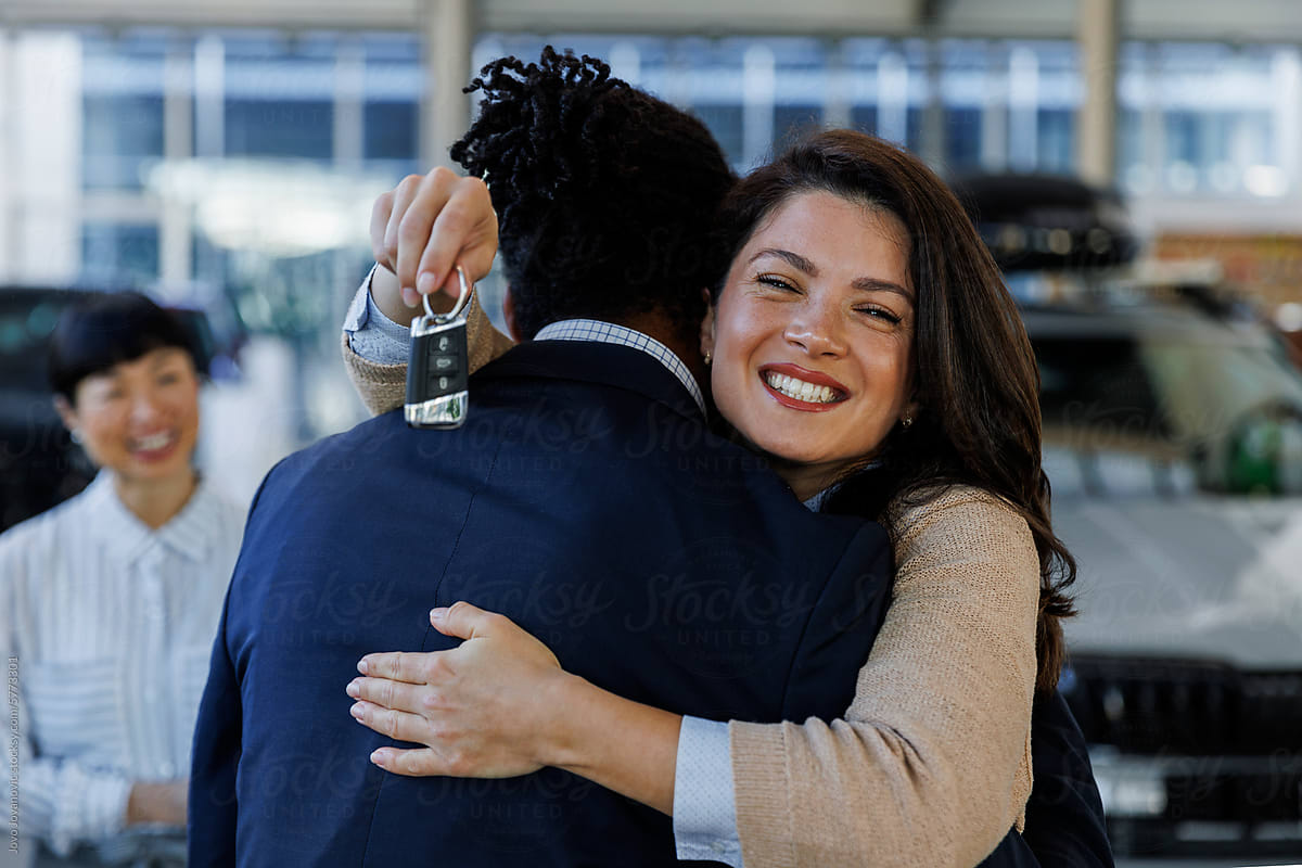 Affectionate couple embracing after new car purchase at dealership