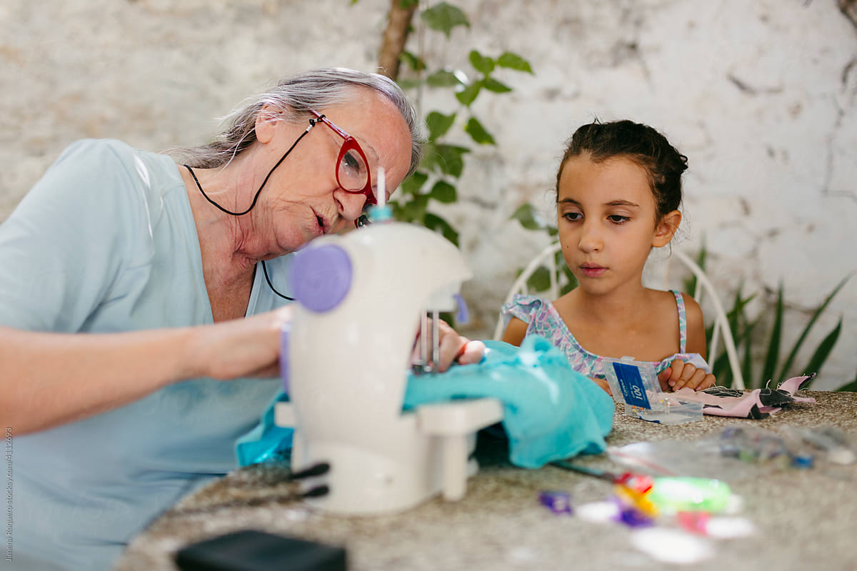 Woman teaching her grandchild to use a sewing machine