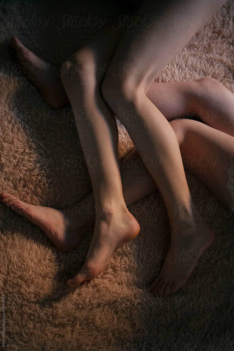 crossed legs of two lesbians on a soft bedspread