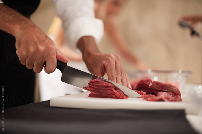 Cutting beef meat on a board with a professional knife