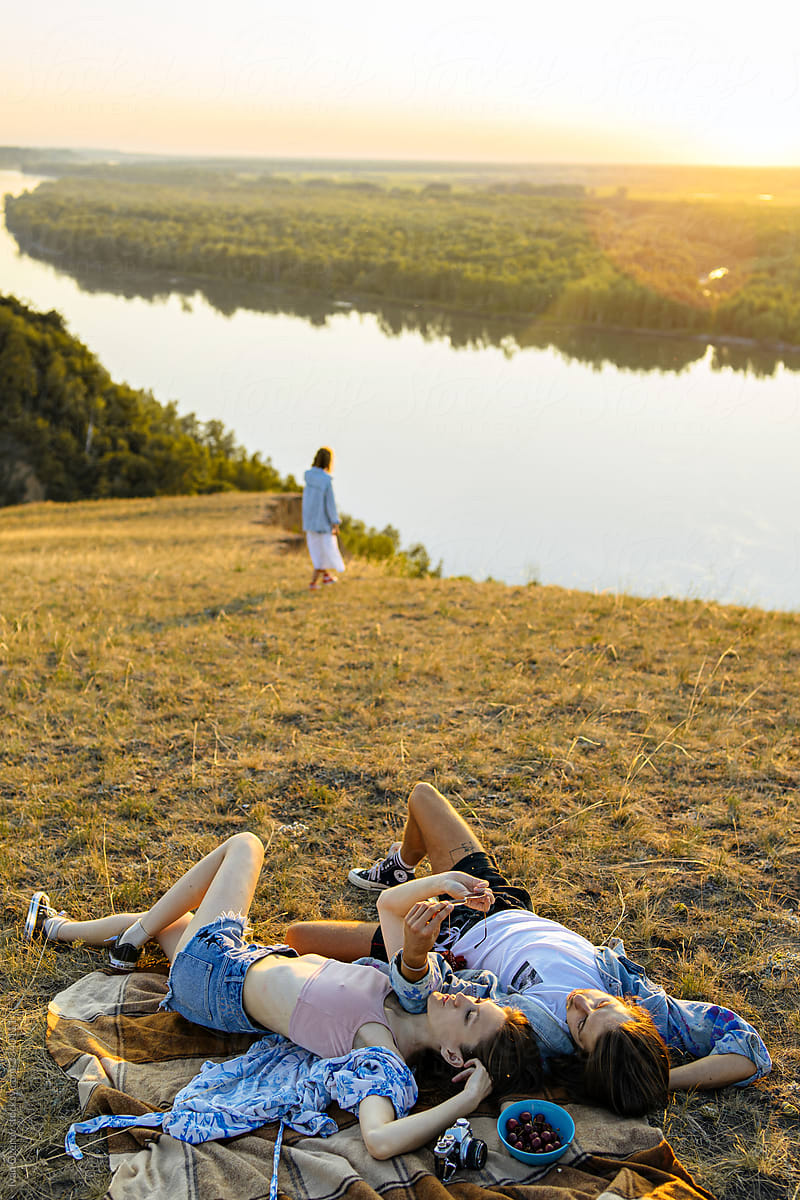 happy carefree young people are resting on a green hill