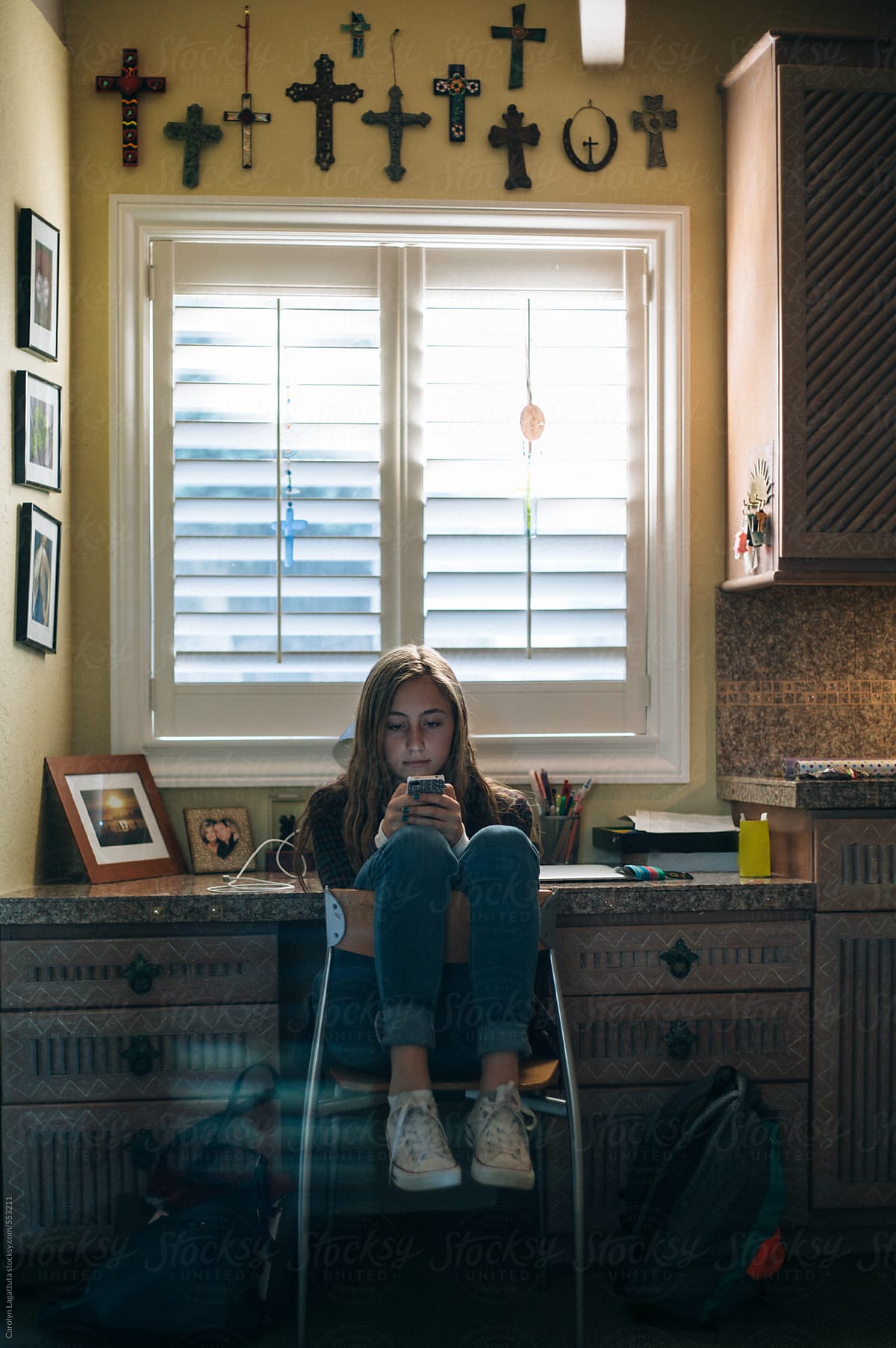 Teen Girl Sitting Backward In A Chair At Home Texting On Her Phone