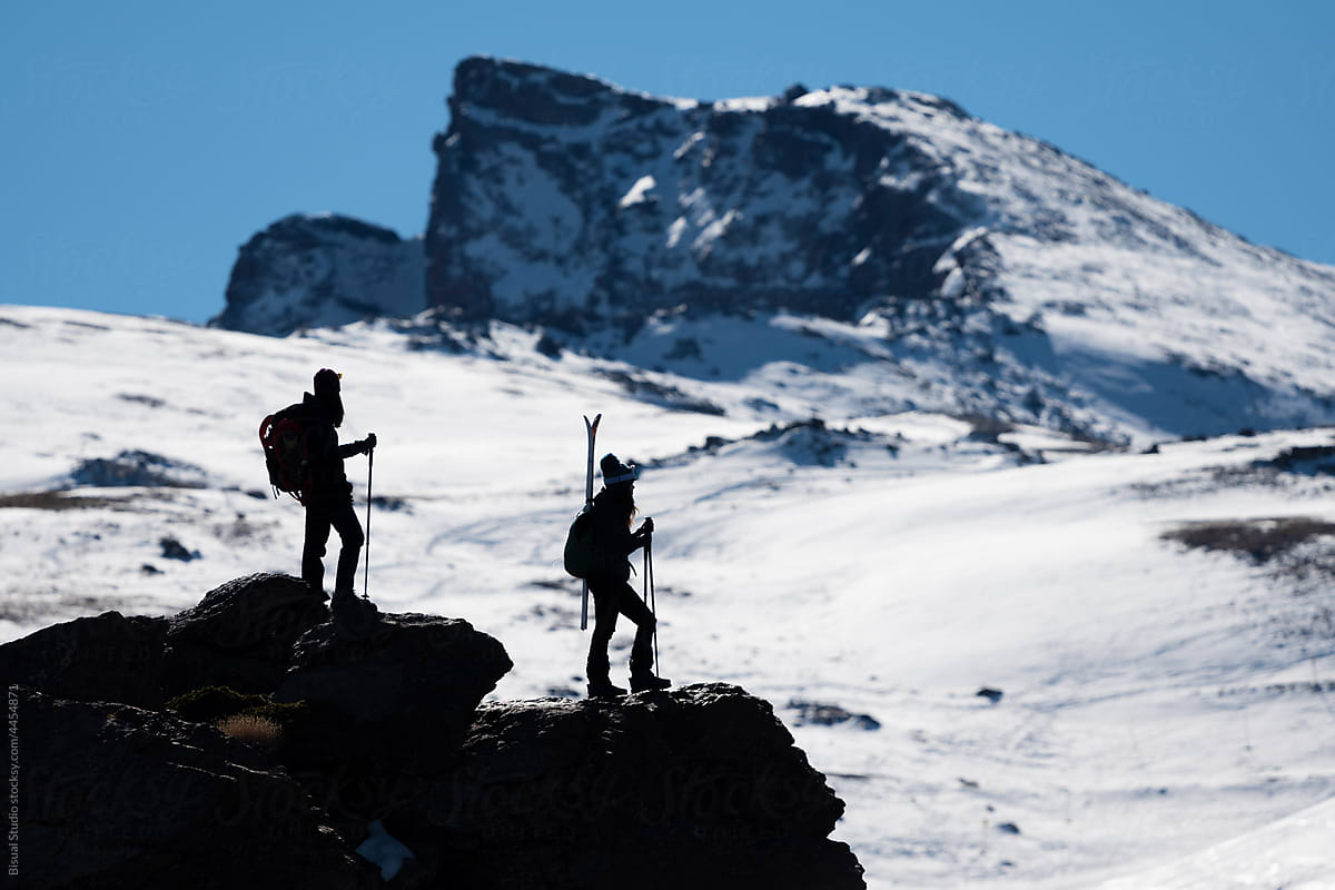 Skiers on rock in snowy mountains