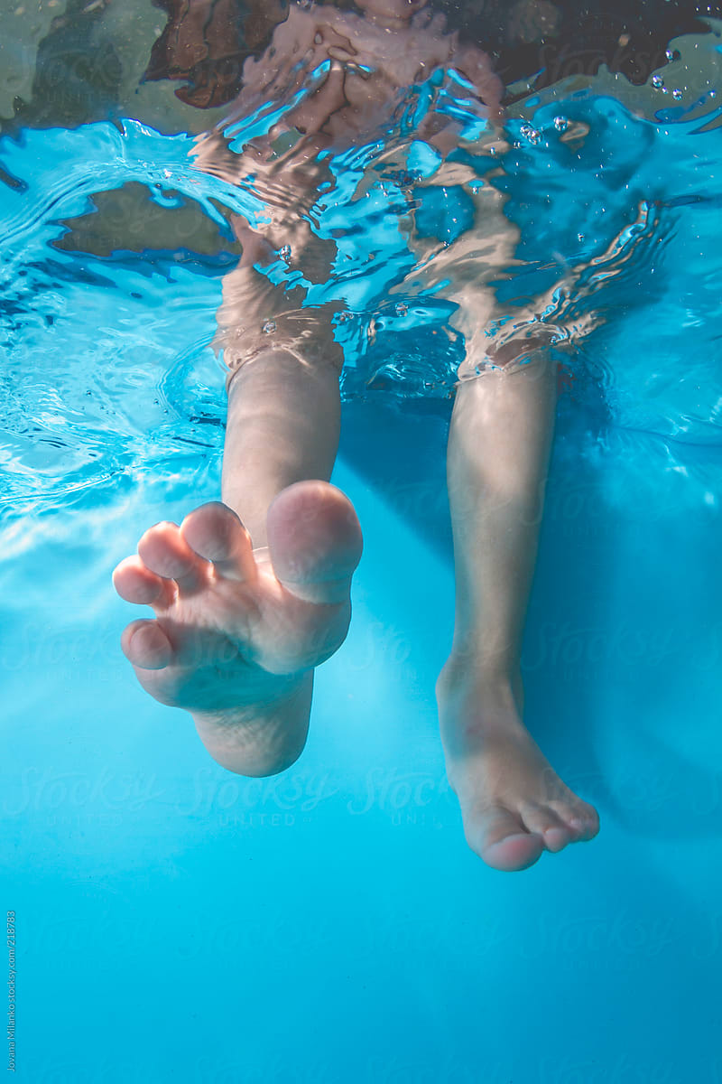Kid\'s feet in the pool underwater