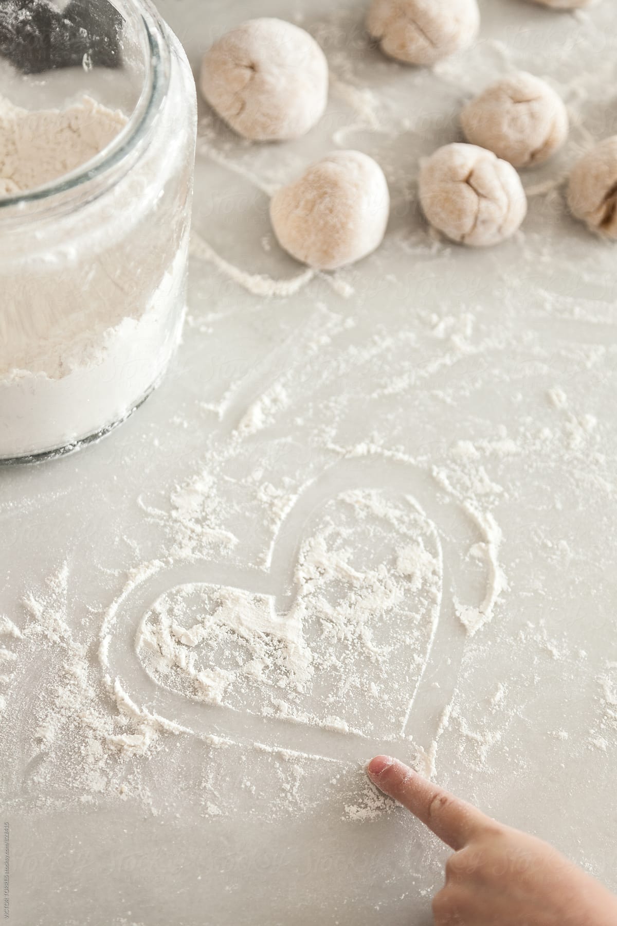 Closeup of a Little Girl Hand Drawing a Heart with Flour