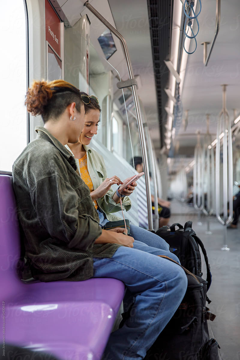 Woman sharing mobile phone content with man traveling in a metro