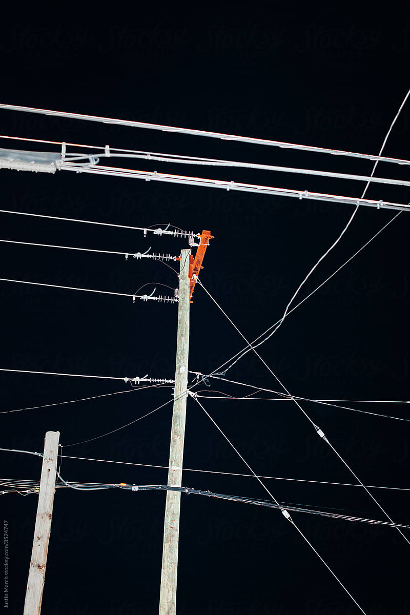 A group of intersecting power lines at night.