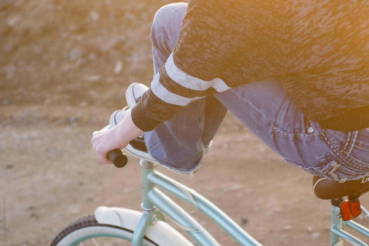 Young teen girl with her feet up on handle bars of bike.